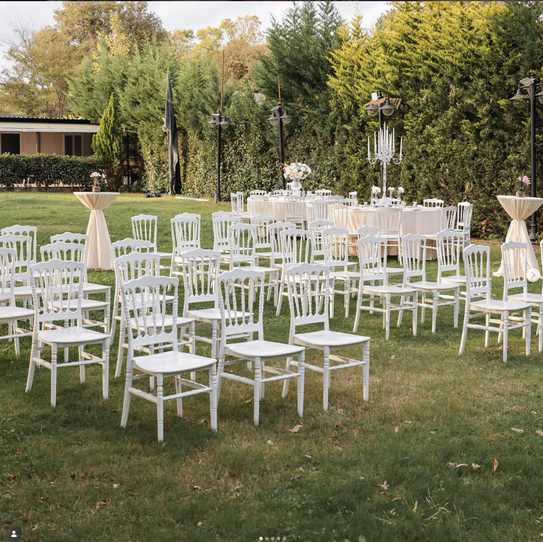 Outdoor ceremony setup at Kemer Garden with white Napoleon chairs and cream draped tables