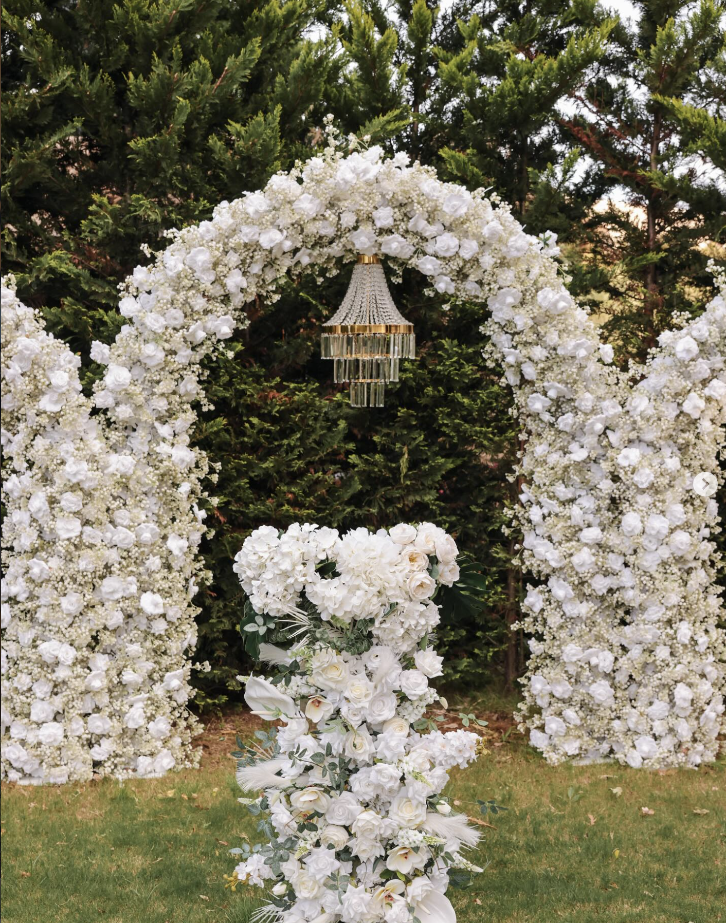 Floral arch and hanging chandelier styled for a wedding ceremony